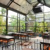 ภายในห้องโถ่งเล็ก Glass House ร้าน ARIS มองเห็นวิวต้นไม้จากด้านนอก ชิลล์ดี
