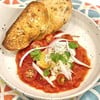 Gently poached eggs in a rich, chunky tomato & bell pepper sauce. on sourdough