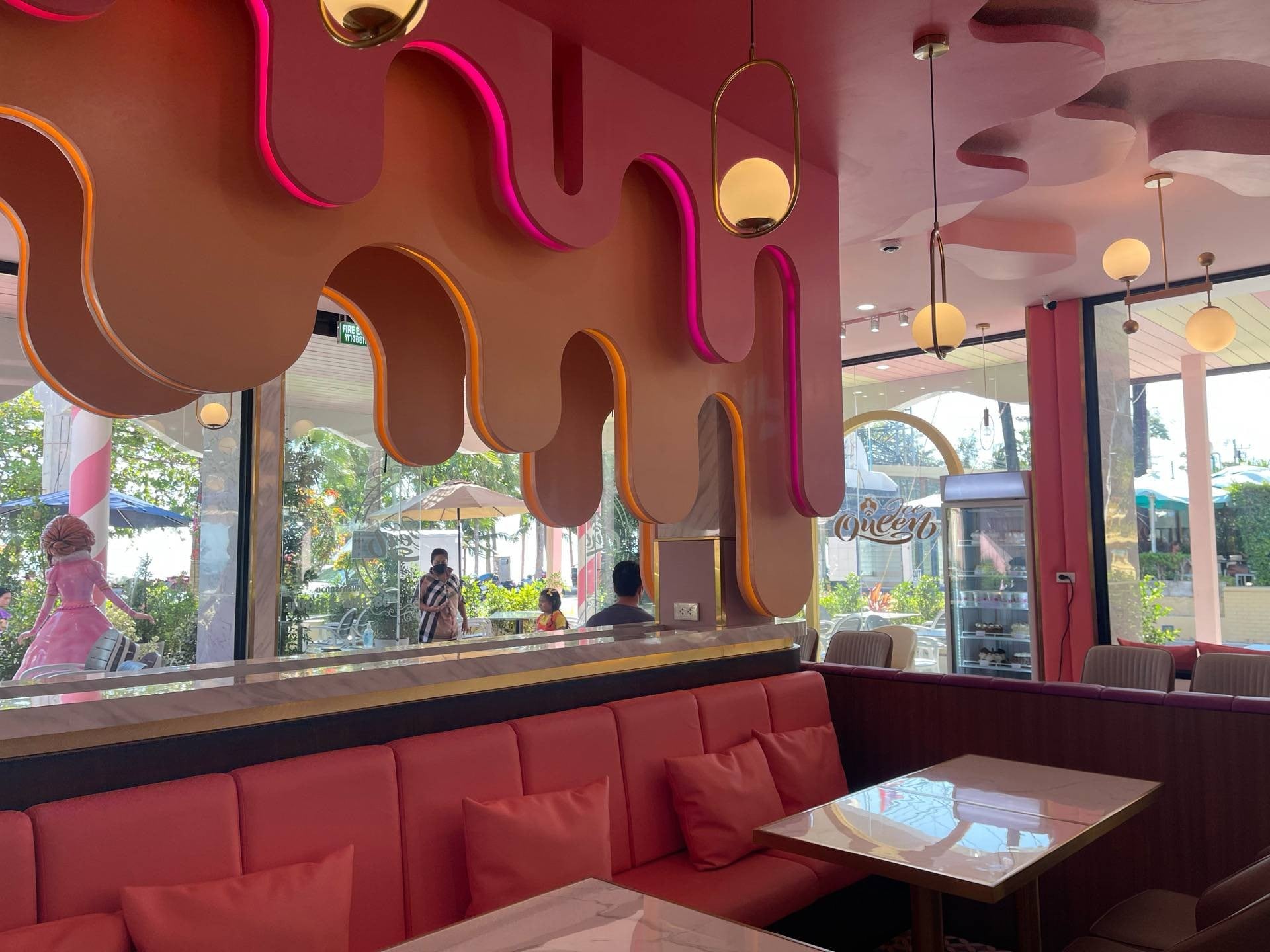 A bright and modern cafe interior with pink and orange decor, booths, and a decorative ceiling.