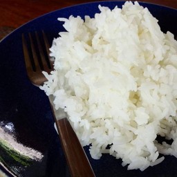 ข้าวสวยในจานและช้อยซ้อมวางอยู่บนโต๊ะไม้