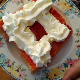 ขนมปังอบ ทาหน้าด้วยแยมสตอรเบอร์รี่ และราดด้วยวิปปิ้งครีม 25฿