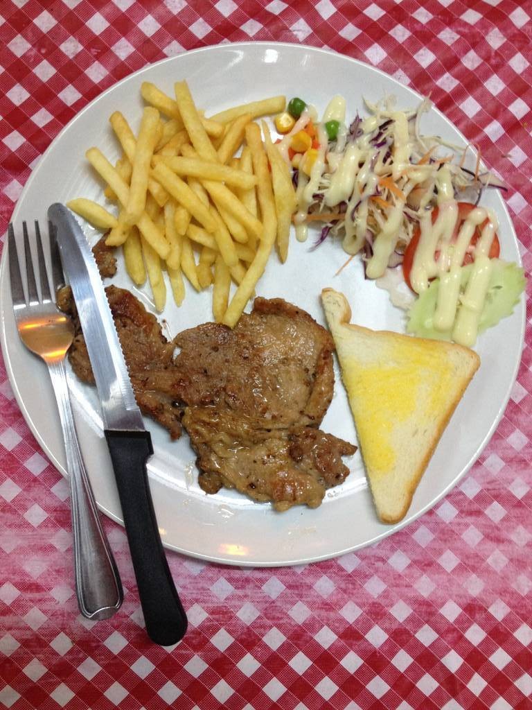 สเต็กหมู เสริฟพร้อม ขนมปัง เฟรนฟราย สลัด